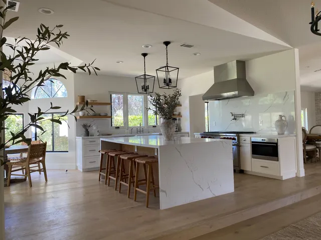 a kitchen with stainless steel appliances granite countertop a table and chairs in it