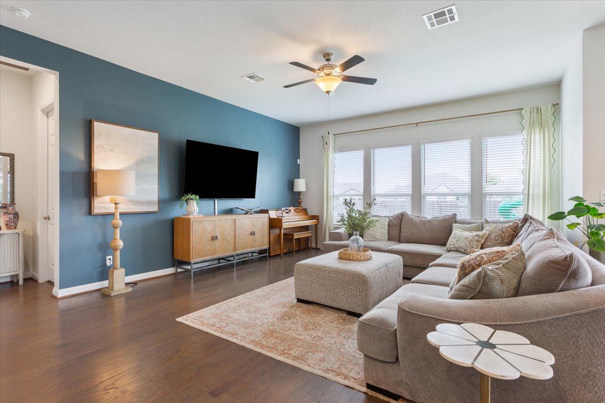 424 Millard Street Georgetown, TX 78628 - Photo 9 of 37 Sun-filled living area featuring rich hardwood flooring and a stylish ceiling fan for comfort.