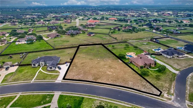 an aerial view of a tennis ground and a cars park side of the road