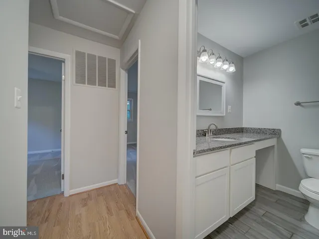 a bathroom with a granite countertop sink and a toilet