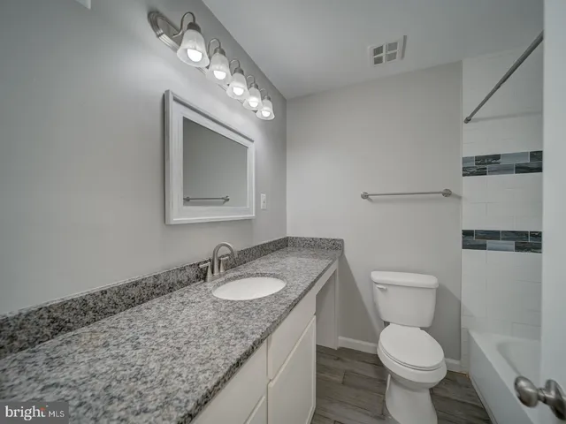 a bathroom with a granite countertop sink a toilet and a mirror
