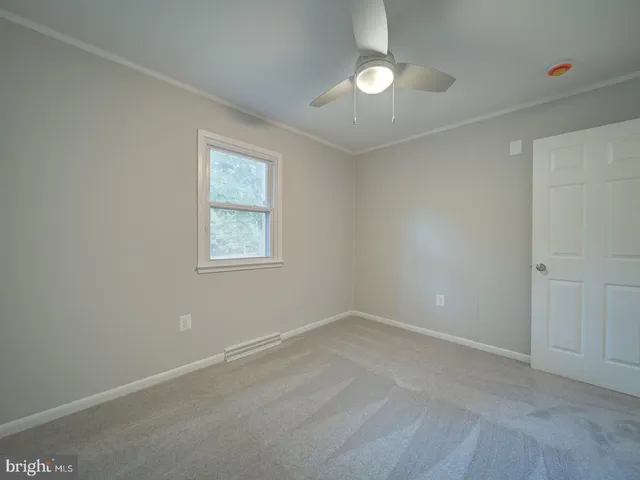 an empty room with windows and ceiling fan
