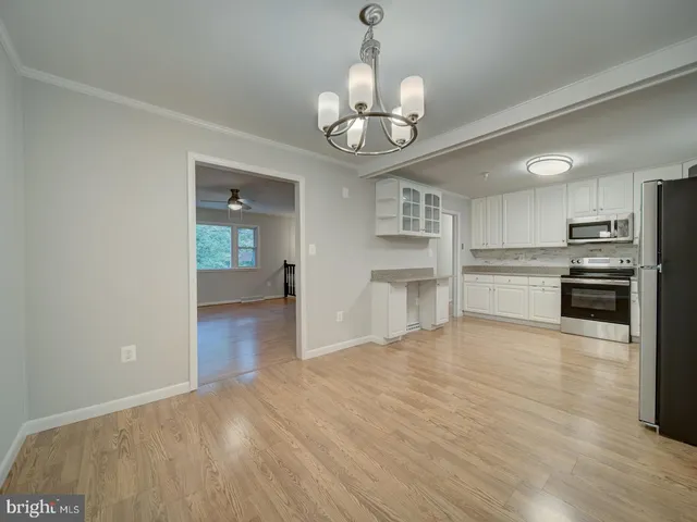 a view of a kitchen with a stove wooden cabinet wooden floor kitchen view and a chandelier