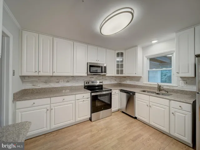 a kitchen with white cabinets appliances and a sink