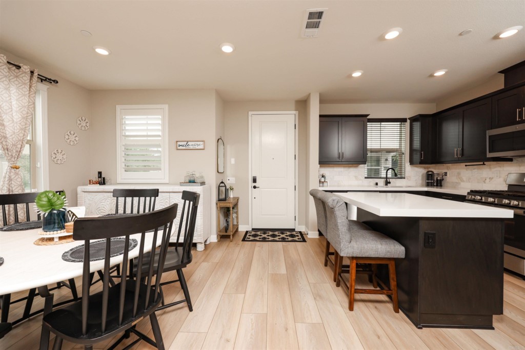 1112 Delpy View Point Vista, CA 92084 - Photo 41 of 62 a kitchen with stainless steel appliances granite countertop a dining table chairs refrigerator sink and cabinets