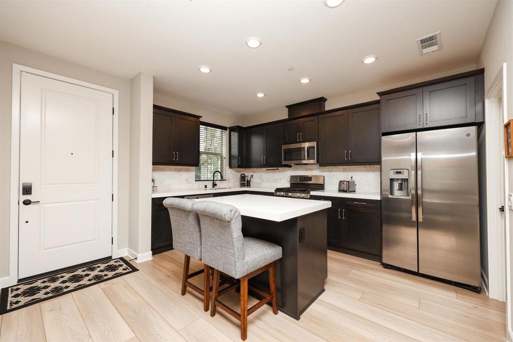 1112 Delpy View Point Vista, CA 92084 - Photo 6 of 62 a kitchen with stainless steel appliances a sink a stove a refrigerator cabinets and a dining table