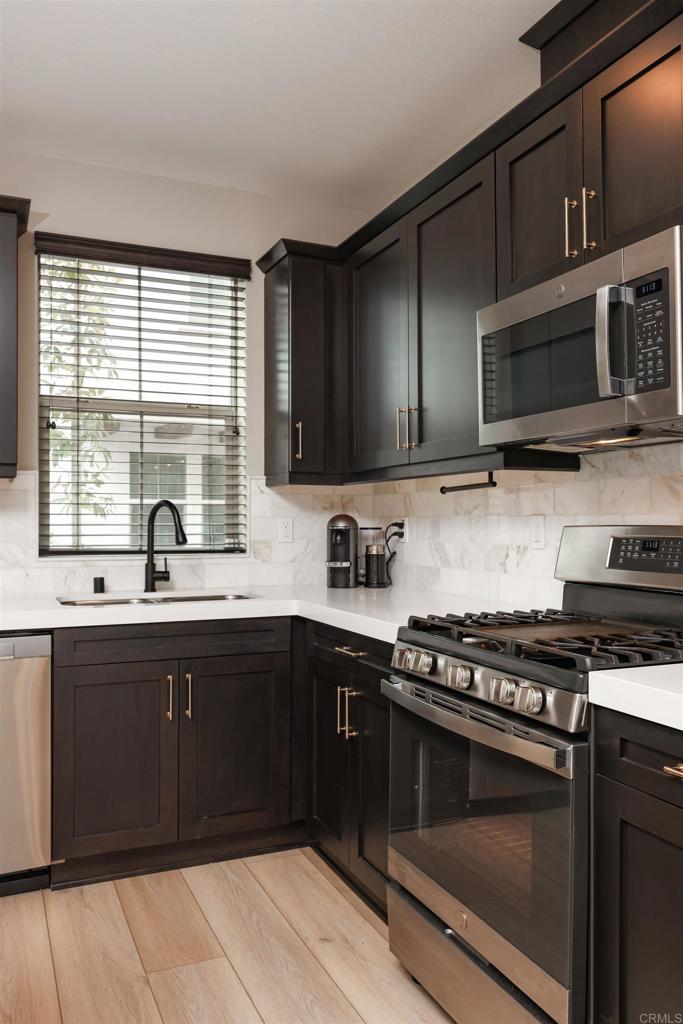 1112 Delpy View Point Vista, CA 92084 - Photo 8 of 62 a kitchen with stainless steel appliances a stove sink microwave and cabinets