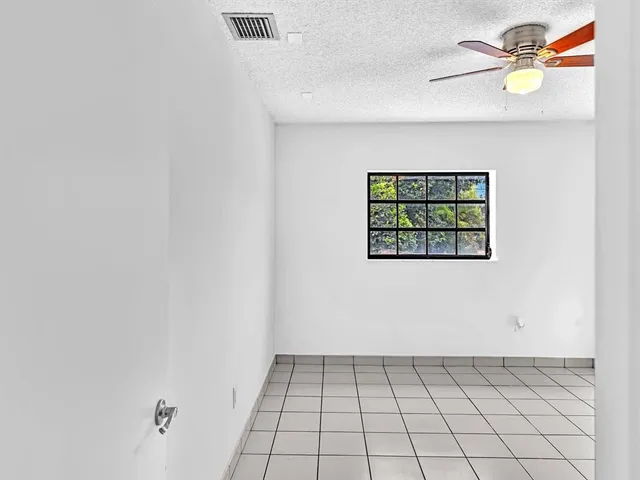 an empty room with windows and fan
