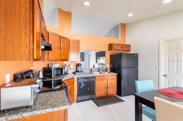 a kitchen with stainless steel appliances kitchen island granite countertop a refrigerator a stove top oven and a dining table with garden view