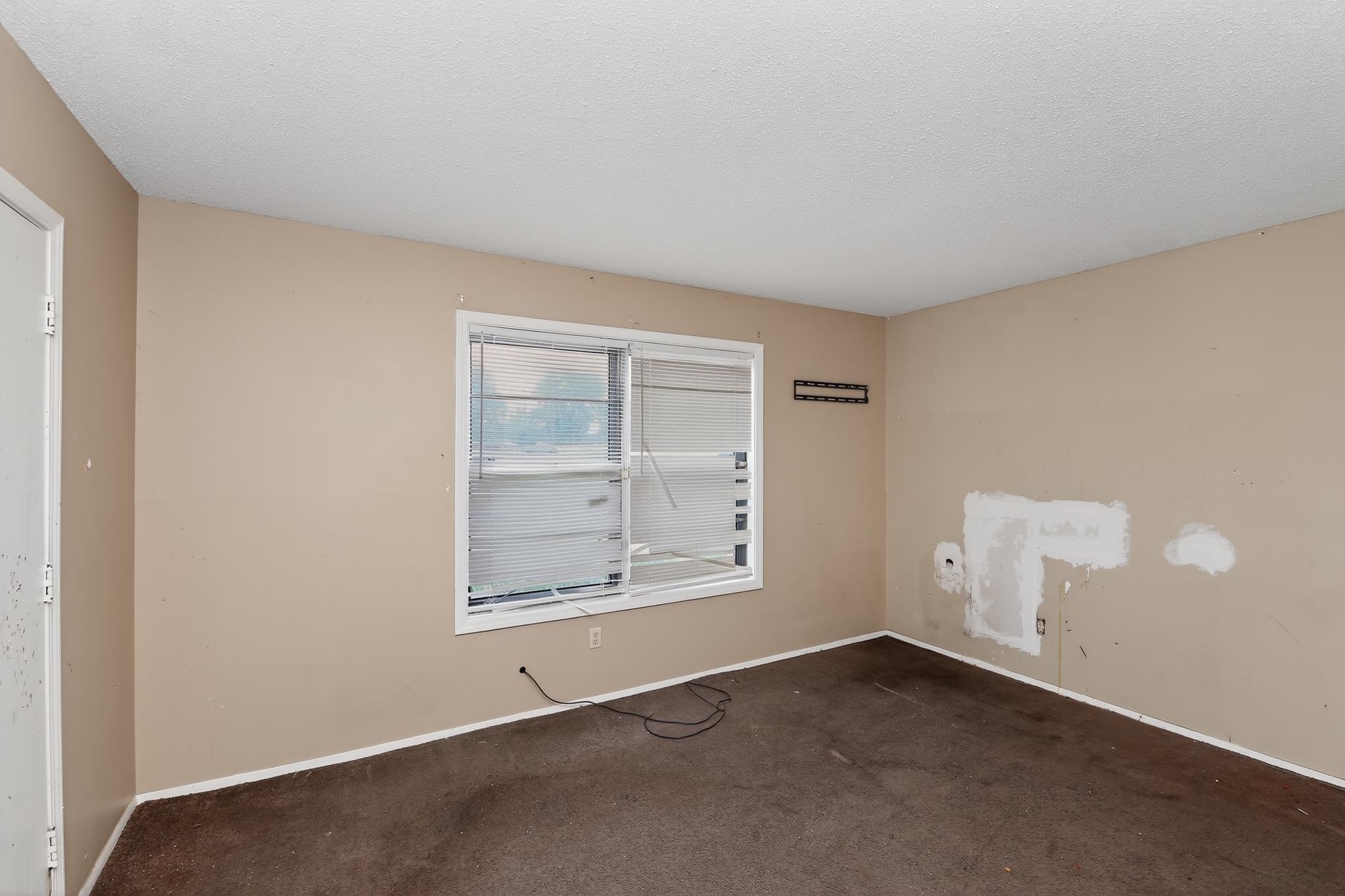 645 Parkrose Road Memphis, TN 38109 - Photo 31 of 32 Neutral-toned walls frame a window with horizontal blinds and a dark carpeted floor