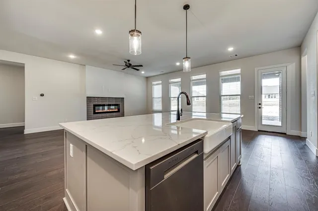 a kitchen with a stove a sink a center island and wooden floor