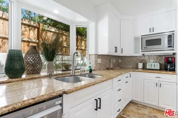 a kitchen with granite countertop a sink stainless steel appliances and white cabinets