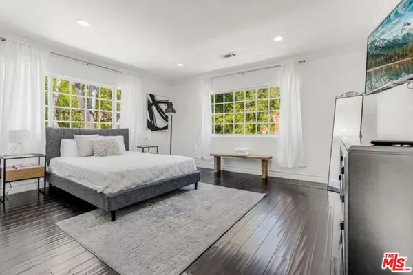 a bed sitting in a spacious bedroom next to a window