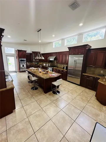 a kitchen with granite countertop a refrigerator and a stove top oven