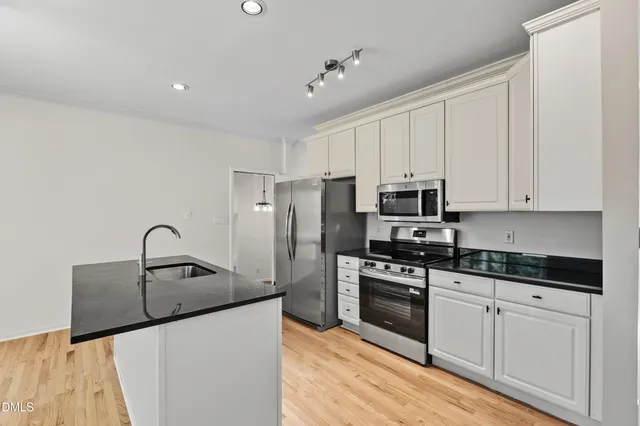 a kitchen with stainless steel appliances granite countertop a sink a microwave and a refrigerator