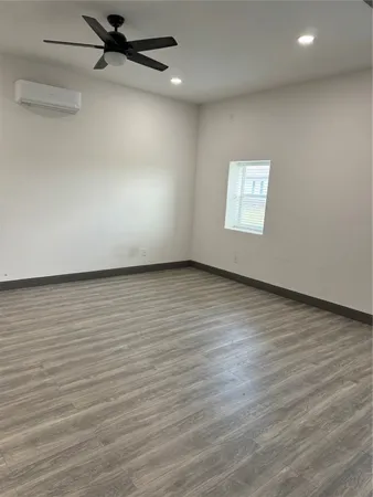an empty room with wooden floor a ceiling fan and windows
