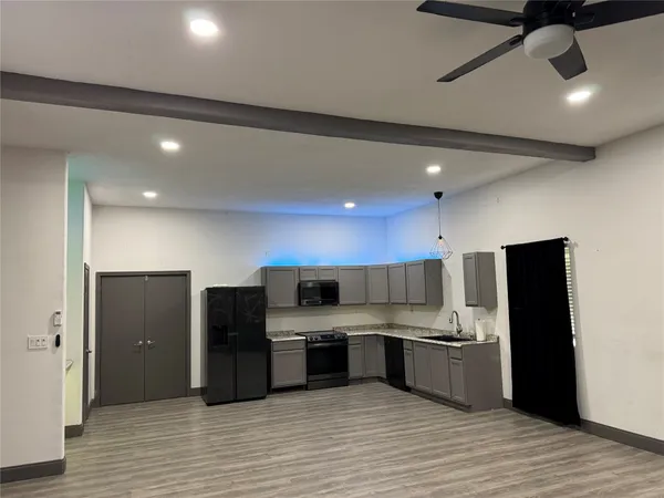 a large kitchen with stainless steel appliances kitchen island a large counter top and a refrigerator