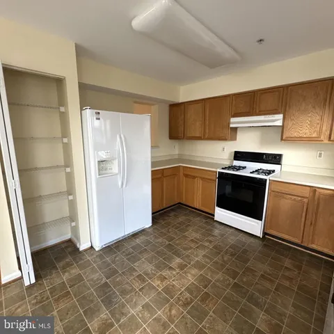 a kitchen with granite countertop a refrigerator and a stove top oven