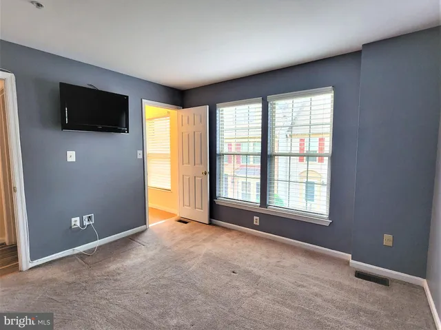 a view of an empty room with a flat screen tv and windows
