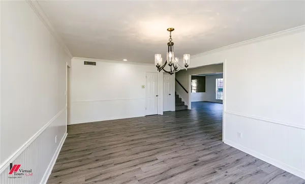 an empty room with wooden floor chandelier and windows
