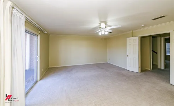 an empty room with chandelier fan and windows