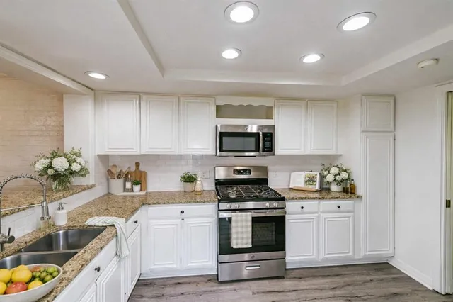 a kitchen with stainless steel appliances a stove a sink a microwave and cabinets