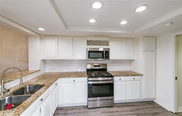 a kitchen with granite countertop a sink stainless steel appliances and cabinets