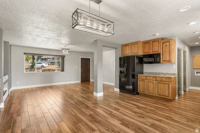 55 Spring Drive Toquerville, UT 84774 - Photo 10 of 36 Kitchen featuring black appliances, a textured ceiling, light wood-style flooring, decorative light fixtures, and light stone counters
