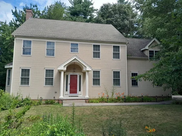 a view of a yard in front of a house with plants and large tree