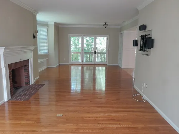 a view of an empty room with wooden floor and a window