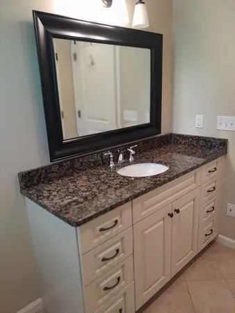 a bathroom with a granite countertop sink and a mirror