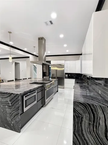 a large kitchen with stainless steel appliances kitchen island granite countertop a stove and a sink