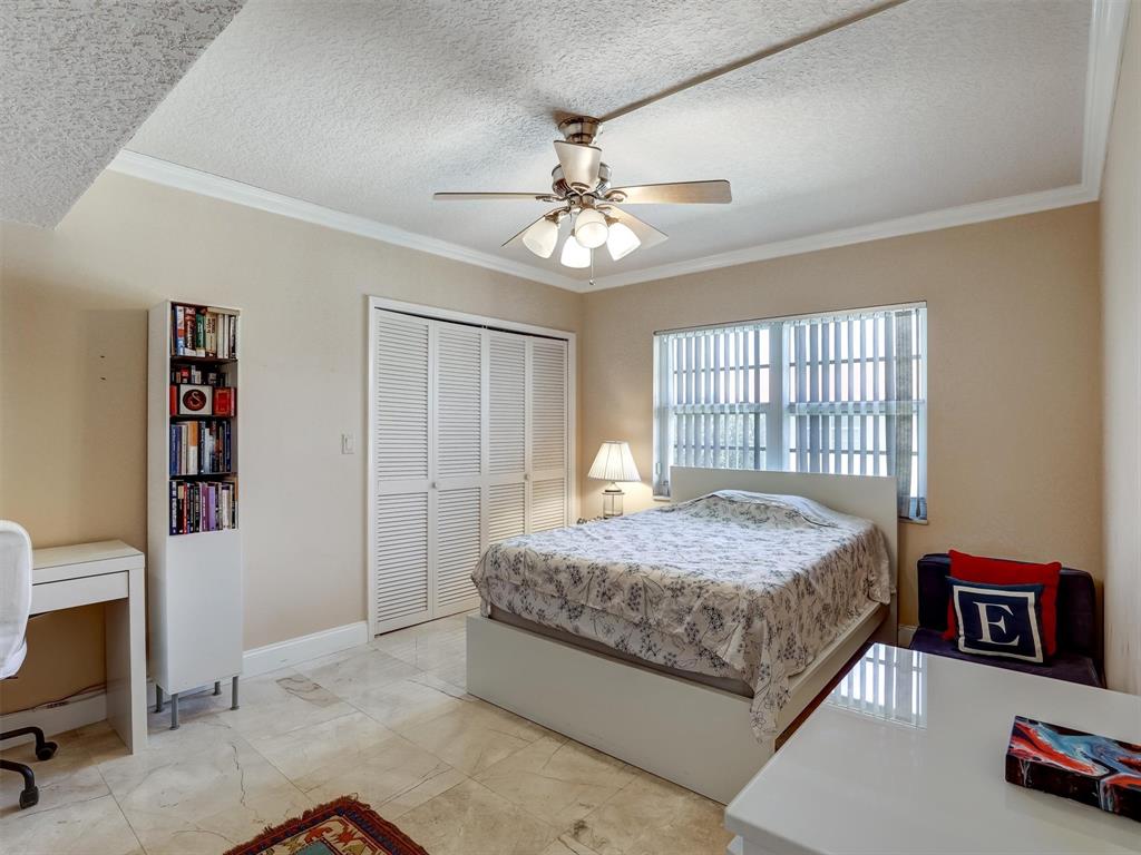 3050 Northeast 48th Court, Unit 401 Lighthouse Point, FL 33064 - Photo 32 of 53 a spacious bedroom with a bed and a chandelier