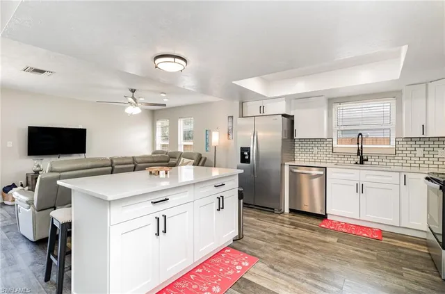 a kitchen with stainless steel appliances kitchen island granite countertop a sink refrigerator and microwave