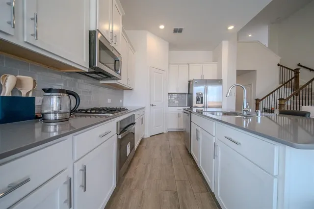 a kitchen with kitchen island granite countertop a sink a counter space stainless steel appliances and cabinets