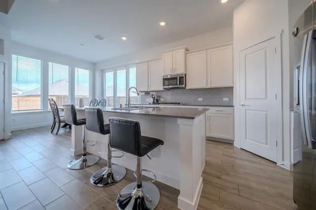 a kitchen with stainless steel appliances granite countertop a stove a sink a dining table and chairs