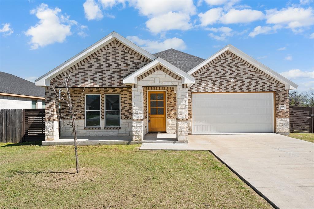 View of front of home featuring an attached garage, brick siding, concrete driveway, stone siding, and roof with shingles