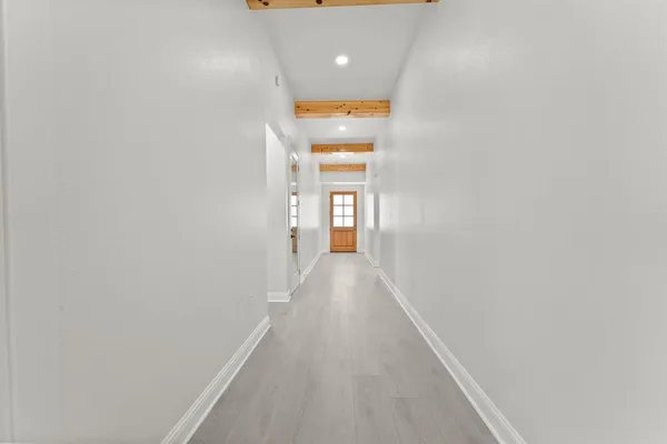 a view of a hallway with wooden floor and a window