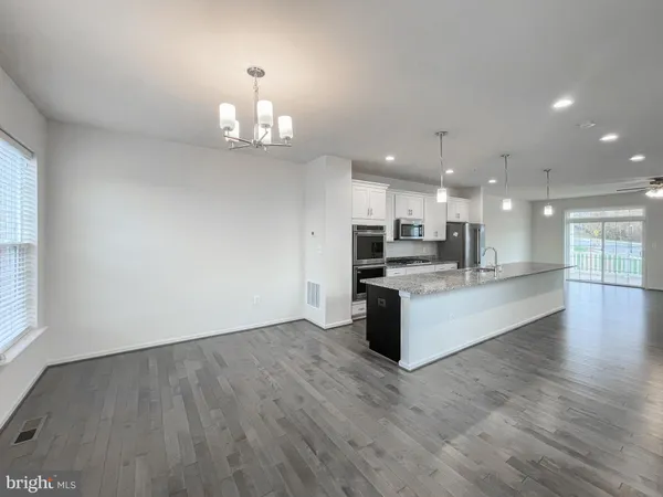 an open kitchen with white cabinets and wooden floor