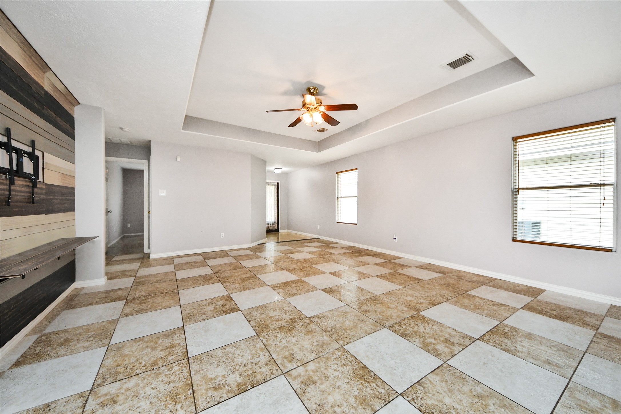 24019 Kingbriar Drive Spring, TX 77373 - Photo 11 of 41 Generous windows with classic blinds illuminate the living space, highlighting the large-format checkered tile flooring and the room's airy, inviting atmosphere.
