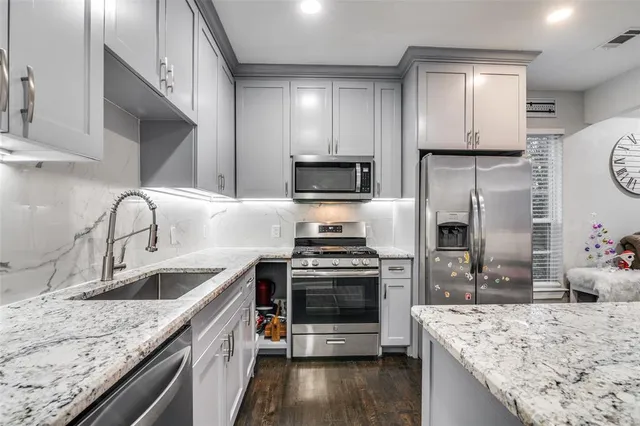 a kitchen with white cabinets sink and stove