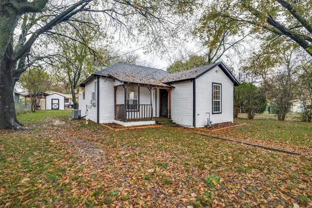 a view of a house with a yard and large tree
