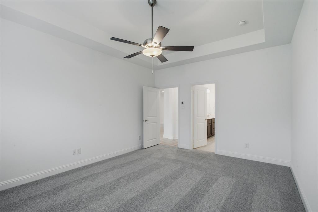 2911 Hanscom Street Forney, TX 75126 - Photo 5 of 40 Spacious room featuring tray ceilings with a ceiling fan light fixture, light gray patterned carpeting, and white baseboards