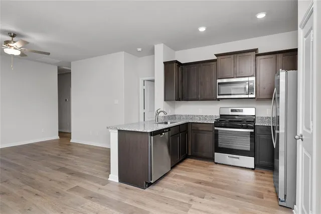 a kitchen with stainless steel appliances granite countertop a stove top oven a sink and dishwasher a refrigerator with wooden floor