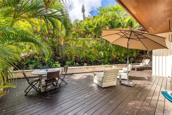 a view of a roof deck with table and chairs under an umbrella with wooden floor