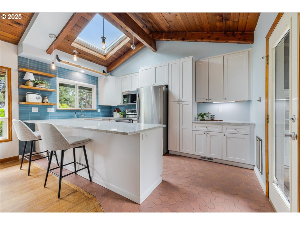 11805 Southwest Belvidere Place Portland, OR 97225 - Photo 11 of 44 a kitchen with stainless steel appliances kitchen island granite countertop a refrigerator a stove a sink and white cabinets with wooden floor