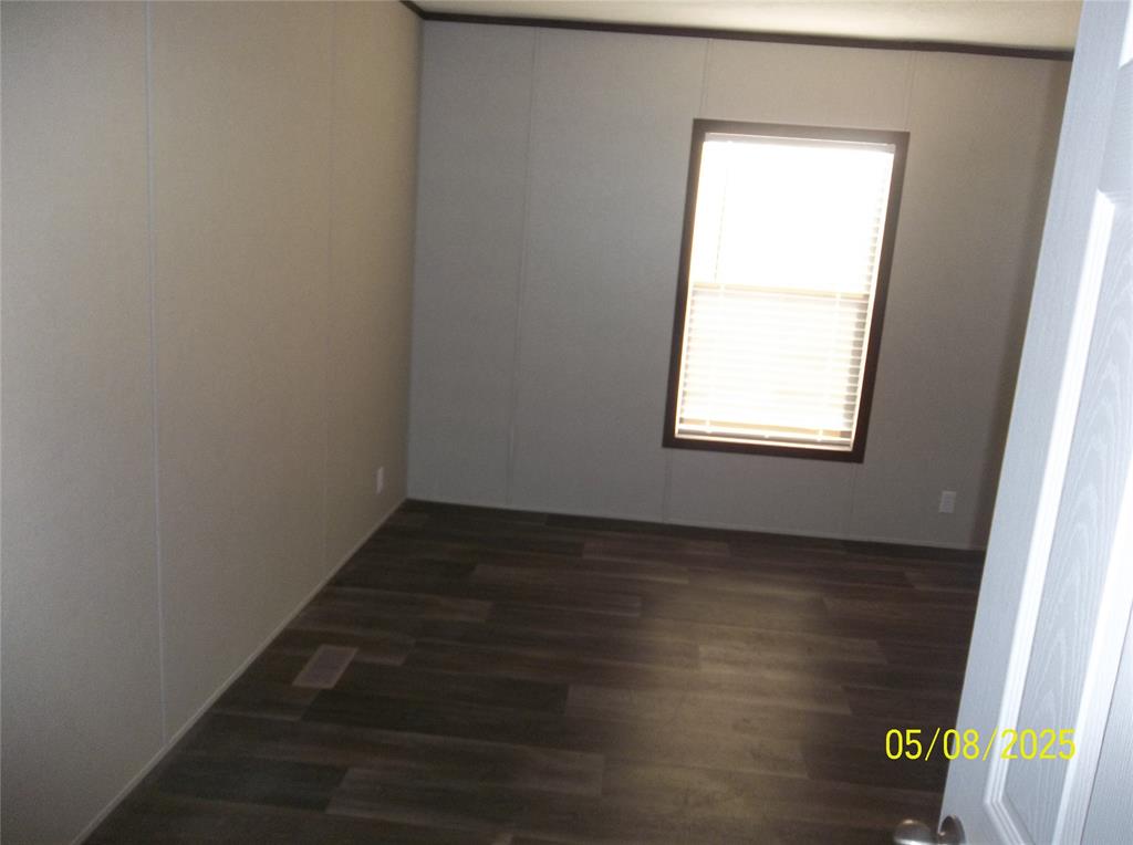 531 Blair Road Waxahachie, TX 75165 - Photo 13 of 40 Unfurnished room with dark wood finished floors and a decorative wall