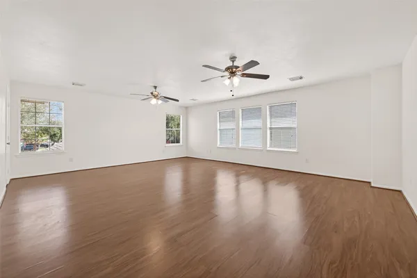 a view of empty room with wooden floor and ceiling fan