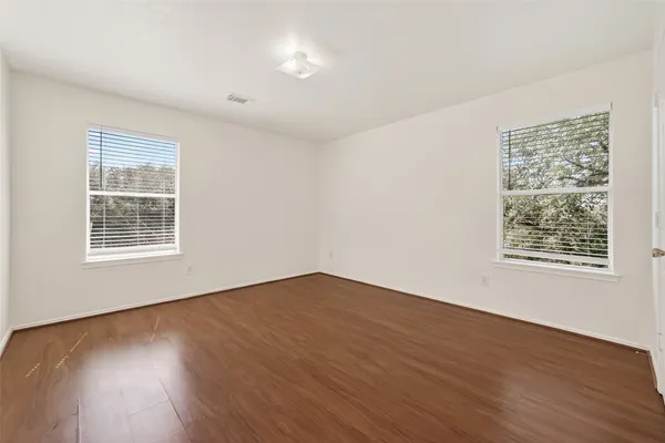 an empty room with wooden floor and windows