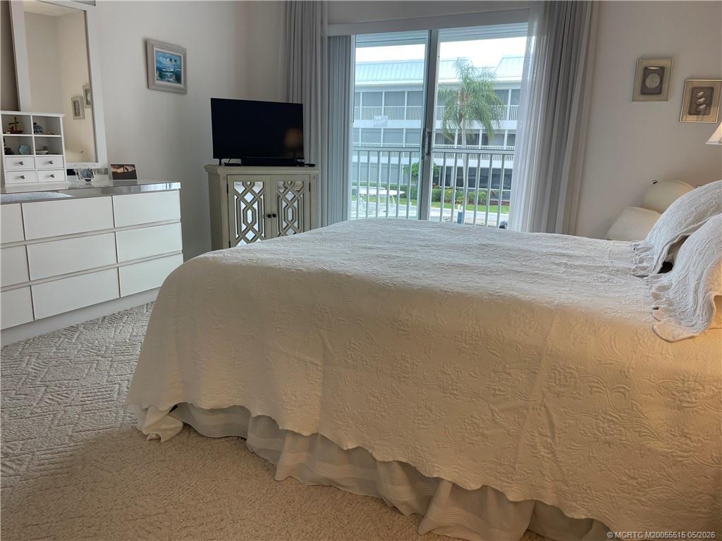 1858 Southwest Palm City Road, Unit 203 Stuart, FL 34994 - Photo 14 of 21 a bedroom with a bed and a flat screen tv